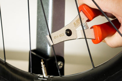 Straight Pull Spoke Pliers 1753/2B-US gripping a straight-pull spoke on a black bicycle wheel rim