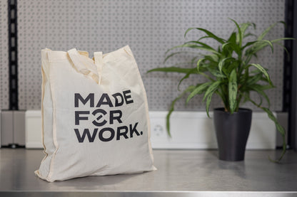 Unior cotton tote bag on a workshop bench beside a potted plant, Made For Work slogan printed on the front