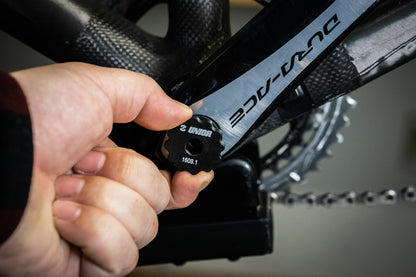 Mechanic fitting Unior 1609.1 preload cap tool to a Shimano Dura-Ace Hollowtech II crank arm on a road bike