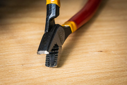 Unior 407/4P pliers jaw close-up on a wood bench, serrated gripping teeth that bite onto rounded or stripped bolt heads
