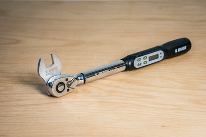 Unior 1613/2CF 15 mm crowfoot wrench fitted to a Unior digital torque wrench on a wood bench, ready for pedal installation