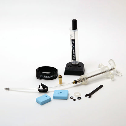 Bleedkit Workshop Shimano bleed kit components arranged on a workshop bench, overflow reservoir, syringe, and pad spacers