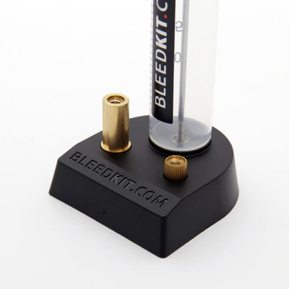 Bleedkit.com syringe stand close-up, black base with brass adapter ports holding a syringe upright for fluid bleeding