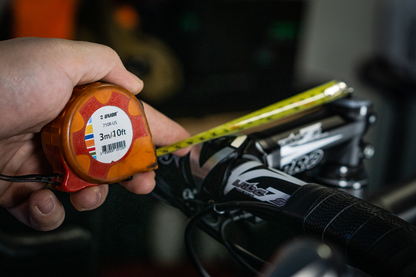 Mechanic using Unior 710R-US tape measure to check a mountain bike handlebar setup on a workshop stand