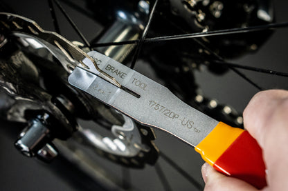 Unior 2-in-1 Disc Brake Tool in use at the rear caliper of a disc-brake road bicycle, cassette visible