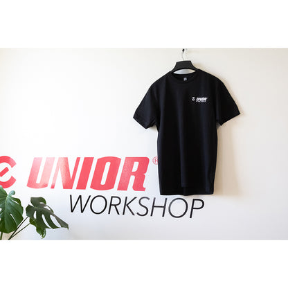 Made For Work tee shirt in black on a hanger, small white Unior Bike Tools chest logo, hung on a Unior Workshop mural wall