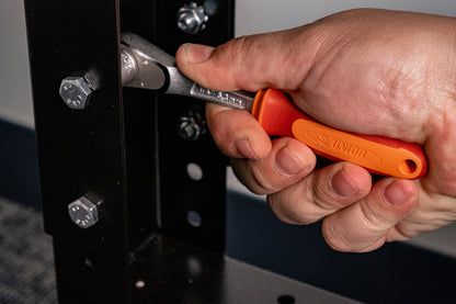 Mechanic using a Unior 1/4-inch socket T-handle to tighten a workbench frame bolt, hand gripping orange Bi-grip