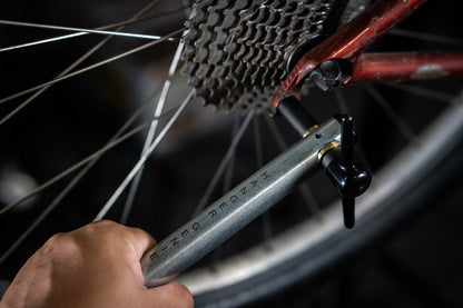 Unior Hanger Genie in use checking rear derailleur alignment on a red bicycle, cassette and spokes visible