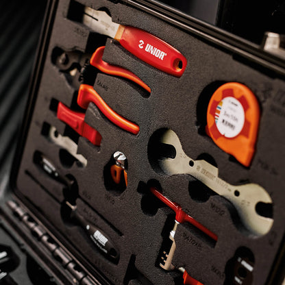 Home Kit foam-tray close-up showing Unior screwdriver, pliers, wrenches and tape measure seated in cutouts inside the case