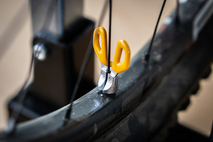 Yellow-handled Unior Professional Spoke Wrench engaged on a spoke nipple at the rim of a mountain bike wheel